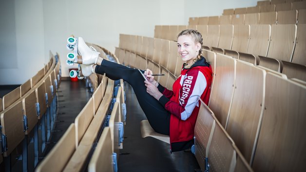 Rollschuhfahrerin sitzt lächelnd im Hörsaal