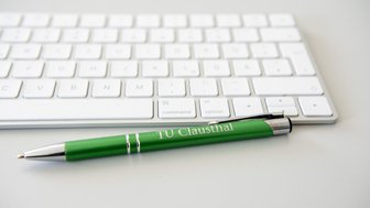 Tastatur und Stift mit TU-Logo